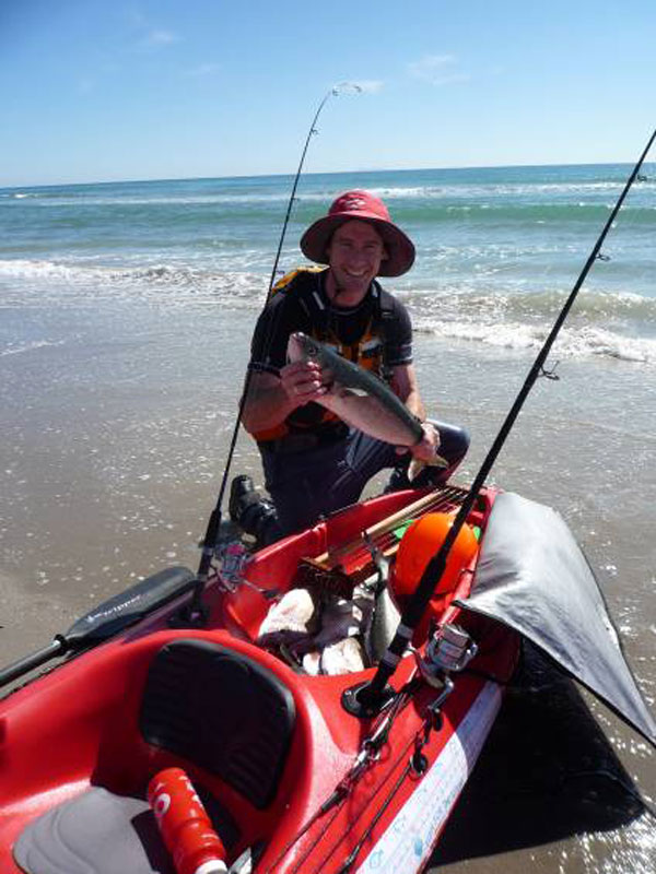 Kayak fisherman displaying the catch on the beach